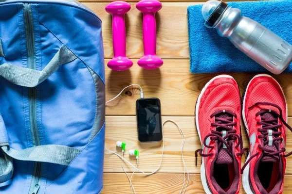bolsa para carregar equipamentos celular e fones de ouvido dois halteres uma toalha um tênis e uma garrafa